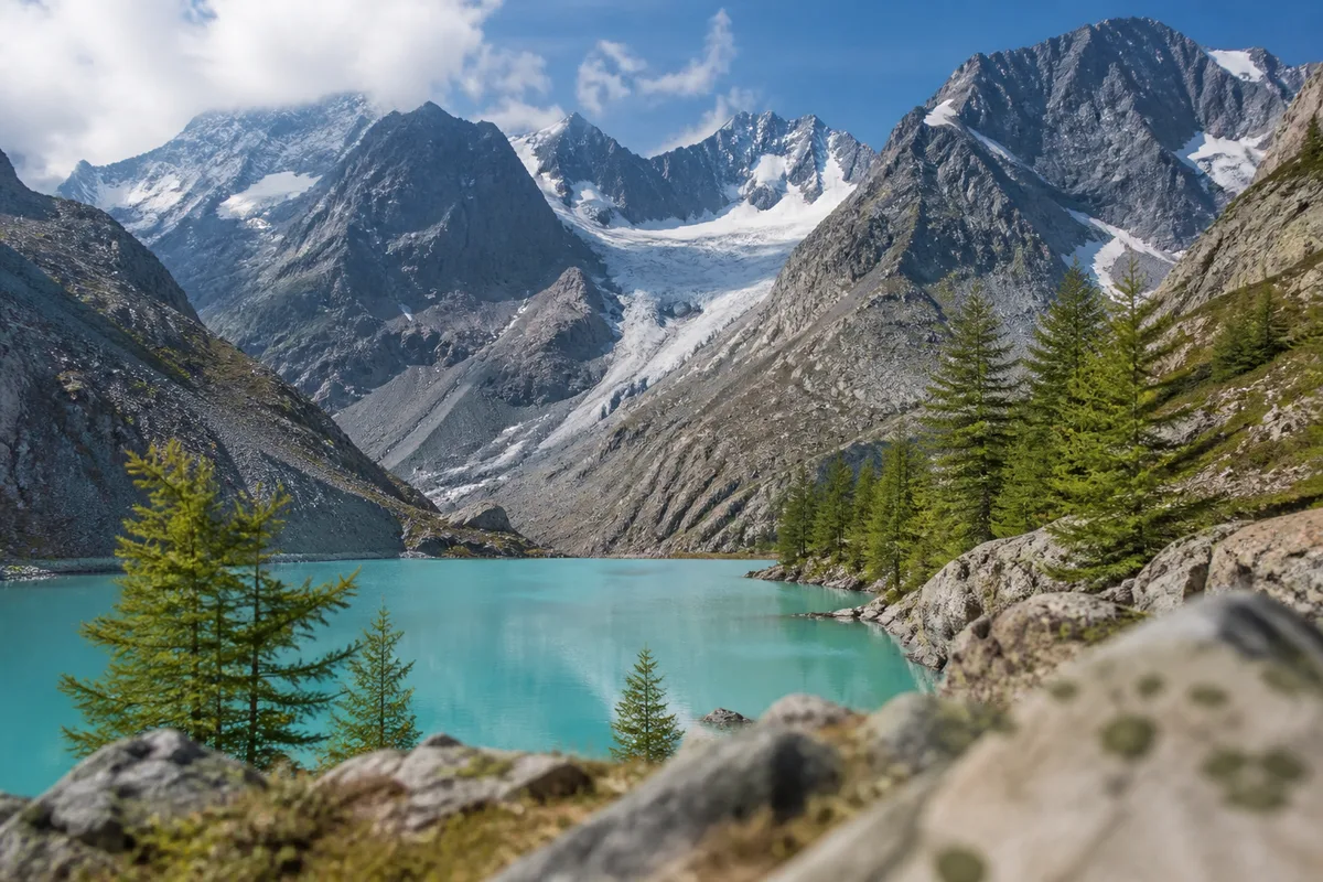 Lac d&rsquo;altitude aux eaux turquoise alimenté par un glacier, bordé de mélèzes dans le massif des Écrins